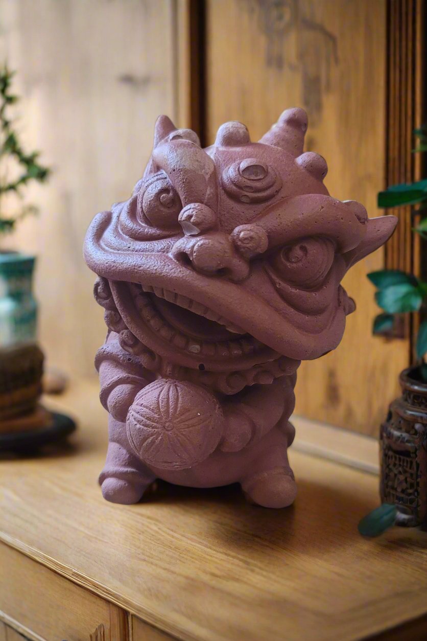 A majestic red lion statue with intricate details, holding a ball in its paw, set against a warm wooden background with Asian-inspired patterns.