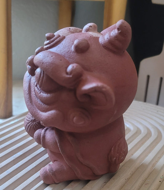 A side view of a lion statue holding a ball in its paw, set against the backdrop of a modern house with clean lines and minimalist decor.