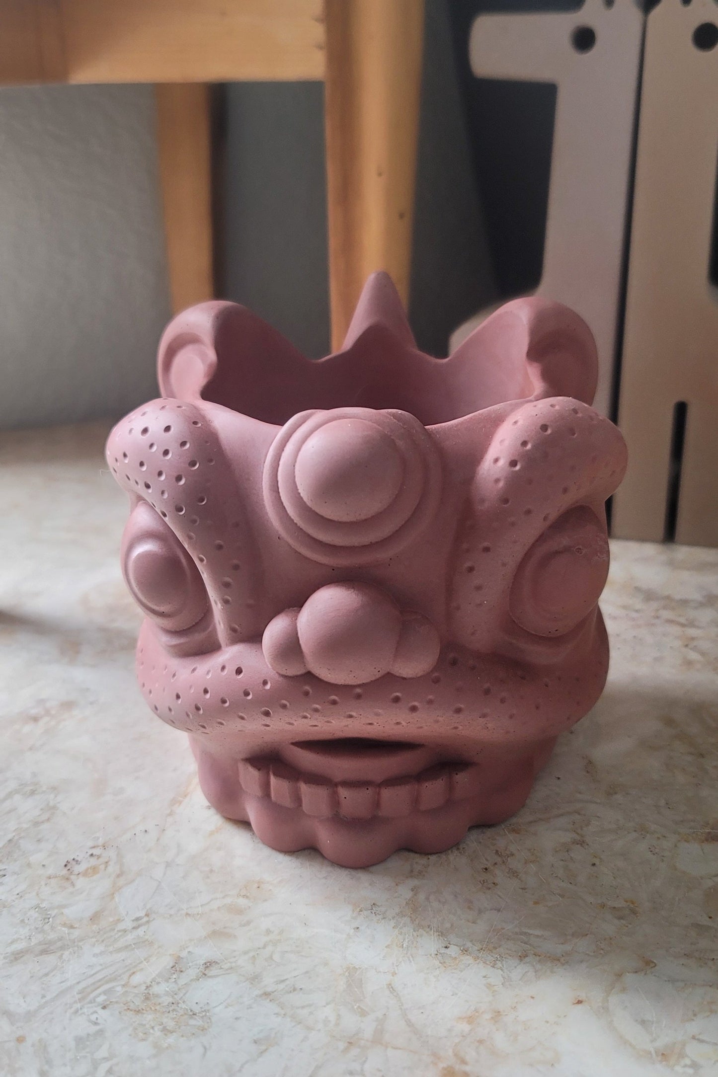 A front-facing sundried tomato lion head planter, showcasing its rich, earthy red hue and intricate detailing. The planter's bold color and fierce expression make it a striking centerpiece, perfect for adding personality and charm to any space.