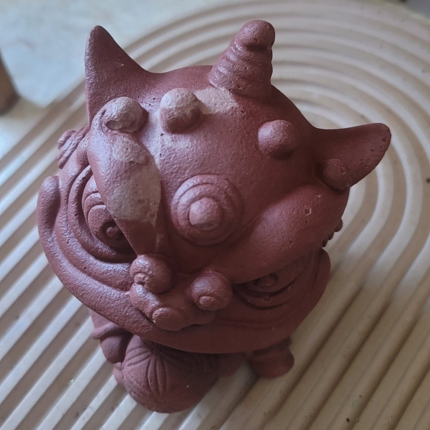 A top view of the lion statue holding a ball, emphasizing its intricate horns, textured eyebrows, and detailed craftsmanship.